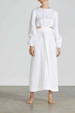 Woman wears BONDI BORN Belize long sleeve linen dress in White with puff sleeves and cut-out dress